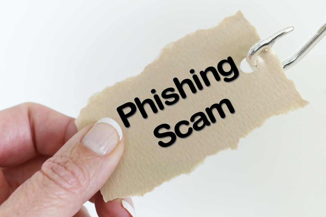 online phishing attempt concept portrayed by hand holding onto paper on fishing hook